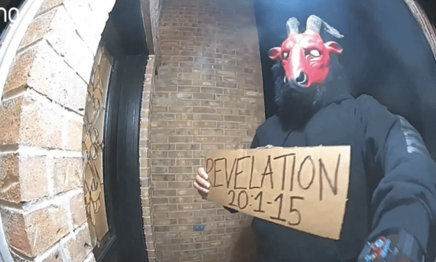 Unidentified man wearing demonic mask and holding sign bearing ominous Bible verse seen walking streets of Texas